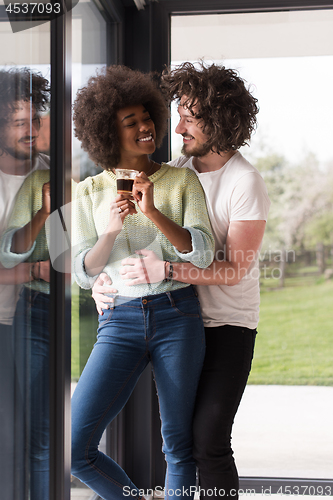 Image of happy multiethnic couple relaxing at modern home indoors