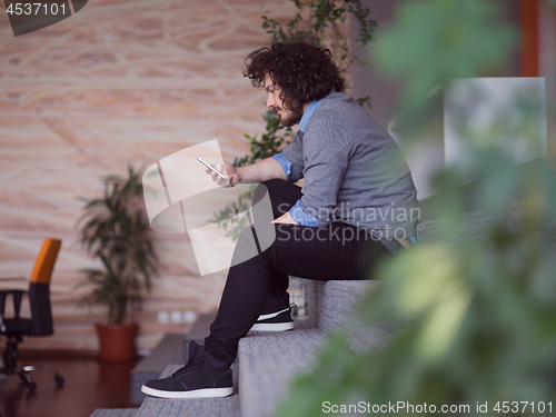 Image of Young casual businessman holding smartphone