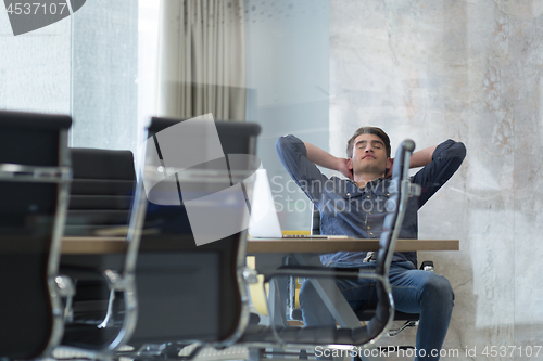 Image of young businessman relaxing at the desk