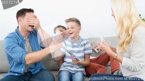 Image of Happy young family playing card game at home.