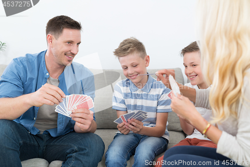 Image of Happy young family playing card game at home.