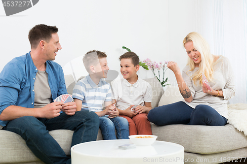 Image of Happy young family playing card game at home.