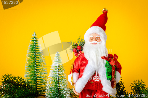 Image of Santa Claus figure with fir trees on yellow background