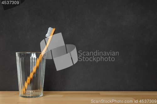 Image of a wooden toothbrush in a glass on black background