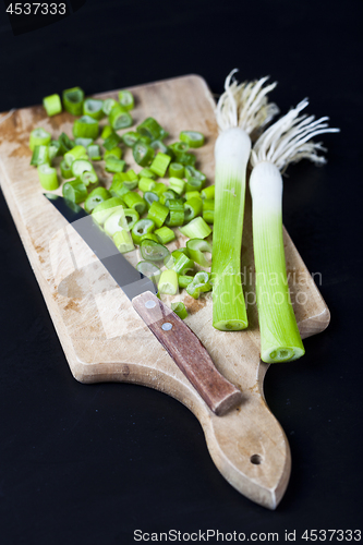 Image of Fresh green organic chopped onions and knife on a cutting board.