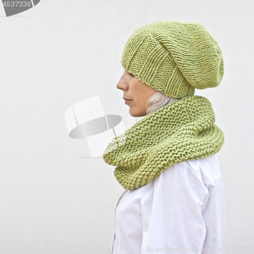 Image of Pretty young woman in warm green knitted hat and snood. 