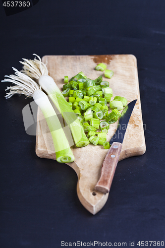 Image of Fresh green organic chopped onions and knife on a cutting board.