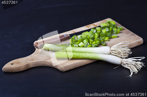 Image of Fresh green organic chopped onions and knife on a cutting board.
