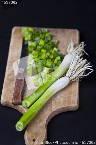 Image of Fresh green organic chopped onions and knife on a cutting board.