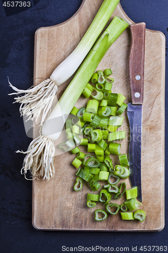 Image of Fresh green organic chopped onions and knife on a cutting board.