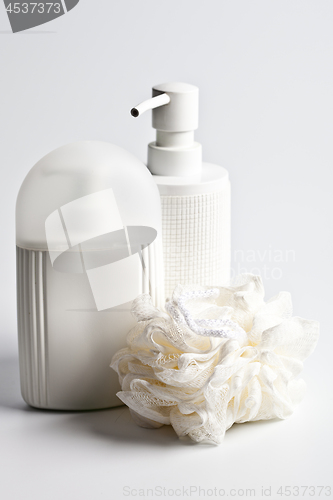 Image of Bath cosmetic products and white sponge on light background.