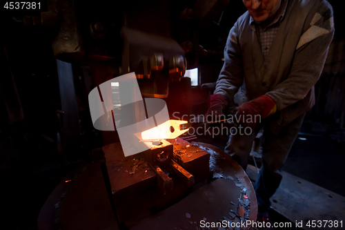 Image of blacksmith manually forging the molten metal