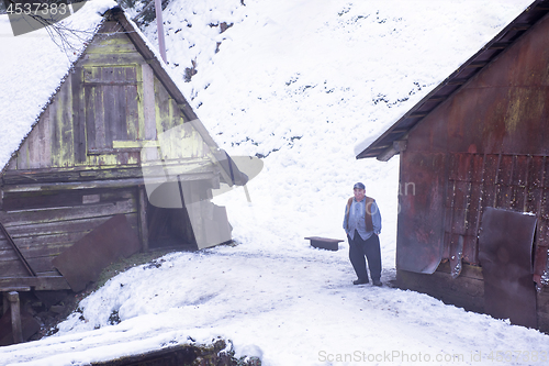 Image of traditional senior blacksmith in front of watermill