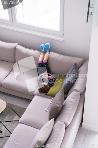 Image of little girl using a smartphone on the sofa at home