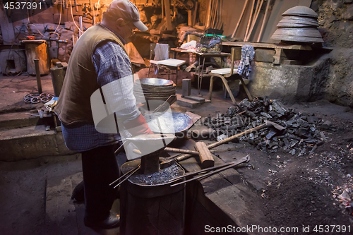 Image of traditional blacksmith manually forging the molten metal