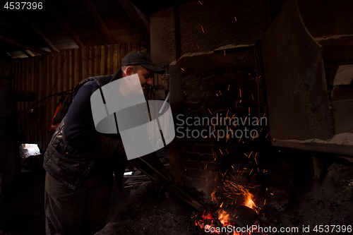 Image of young traditional Blacksmith working with open fire