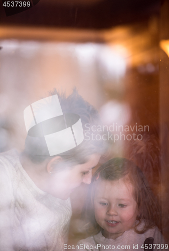 Image of young mother and little cute daughter playing near the window