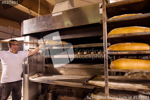 Image of bakery worker taking out freshly baked breads