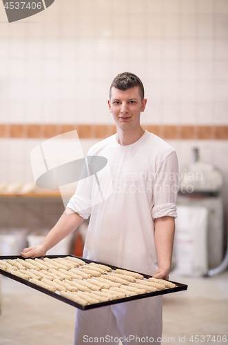 Image of A young baker holding raw product of white dough