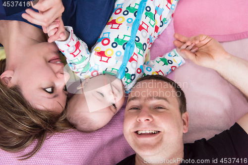 Image of Top view of smiling young couple lying with their baby