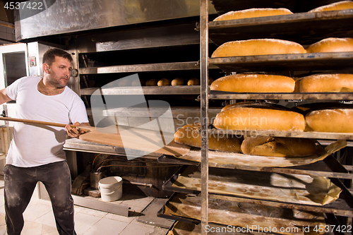 Image of bakery worker taking out freshly baked breads