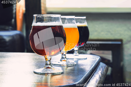 Image of Glasses of different kinds of beer on wooden background