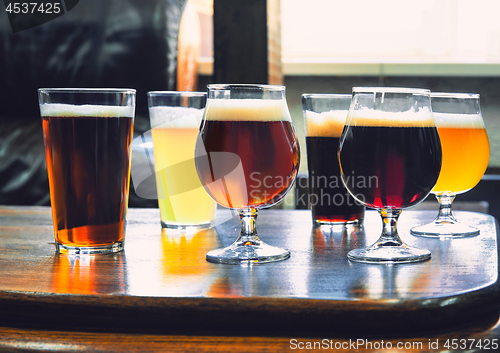 Image of Glasses of different kinds of beer on wooden background