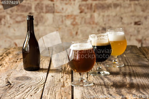 Image of Glasses of different kinds of beer on wooden background