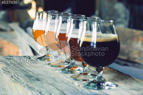 Image of Glasses of different kinds of beer on wooden background