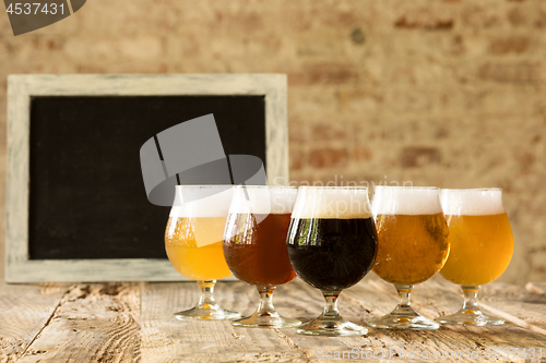 Image of Glasses of different kinds of beer on wooden background