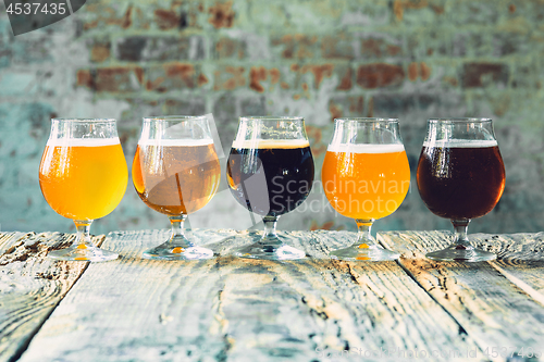 Image of Glasses of different kinds of beer on wooden background