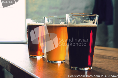 Image of Glasses of different kinds of beer on wooden background