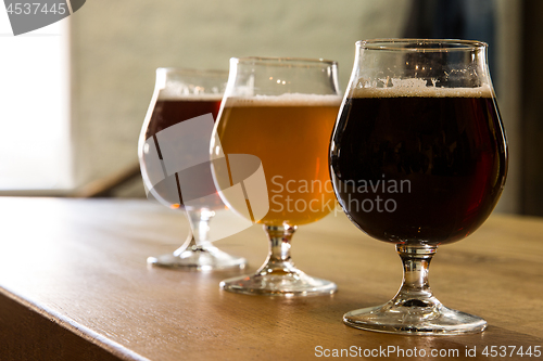 Image of Glasses of different kinds of beer on wooden background