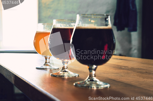 Image of Glasses of different kinds of beer on wooden background