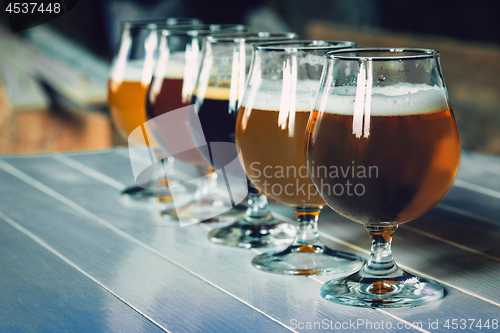 Image of Glasses of different kinds of beer on wooden background