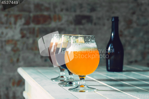 Image of Glasses of different kinds of beer on wooden background