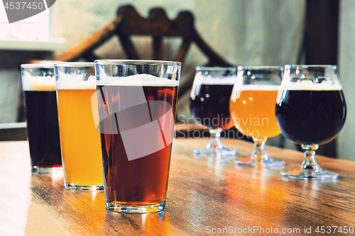 Image of Glasses of different kinds of beer on wooden background