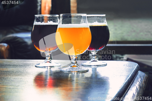 Image of Glasses of different kinds of beer on wooden background