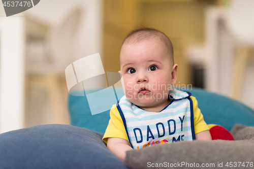 Image of baby boy sitting between the pillows on sofa