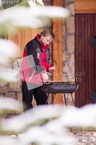 Image of young man cooking meat on barbecue