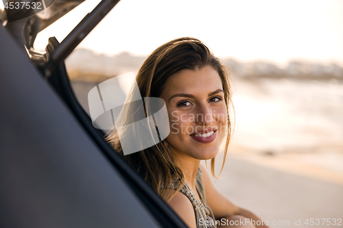 Image of Girl near the beach sitting on the car