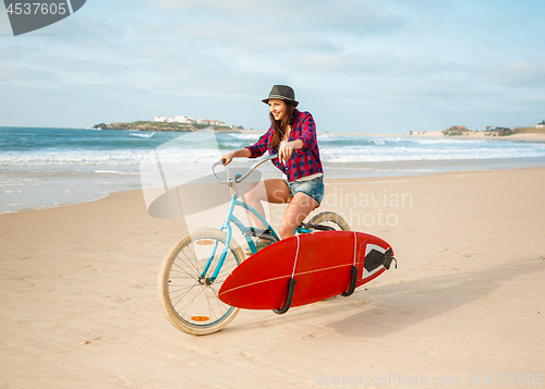 Image of Surfer girl riding a bicyicle