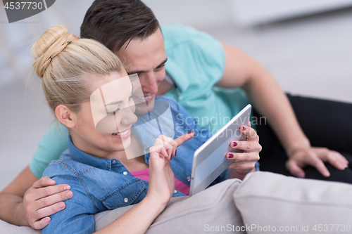 Image of couple relaxing at  home with tablet computers