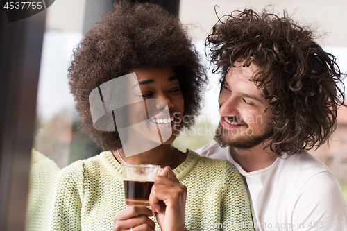 Image of happy multiethnic couple relaxing at modern home indoors