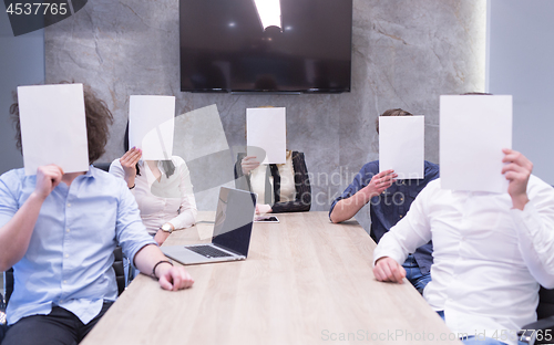 Image of startup business team holding a white paper over face