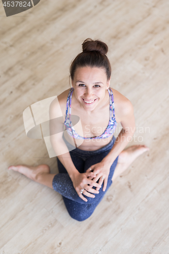 Image of Fit sporty active girl in fashion sportswear sitting on the floor in yoga studio. Active urban lifestyle