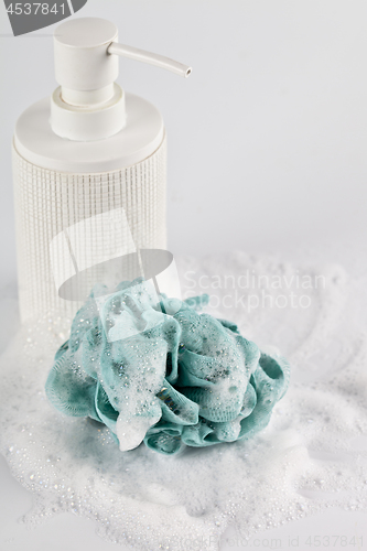 Image of Liquid soap, green sponge and foam on light background.