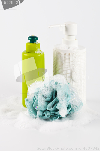 Image of Bath cosmetic products, green sponge and foam on light backgroun