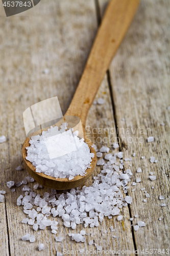 Image of Wooden spoon with sea salt closeup on wooden rustic table.