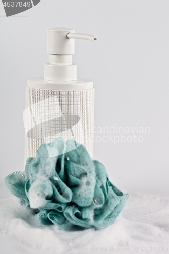 Image of Liquid soap, green sponge and foam on light background. 